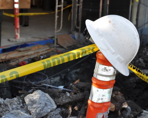 A contractor's hardhat on top of a orange construction site cone.