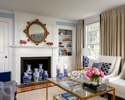 A living room with a popcorn ceiling and traditional interior design with blue tile vases and lamps and a modern glass coffee table.