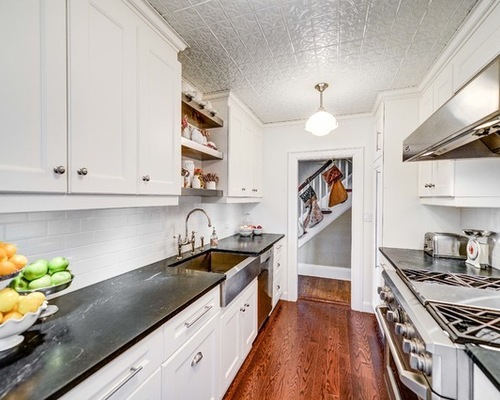 A kitchen with a warm wood ceiling, white cabinets, and shiny hardwood floors.