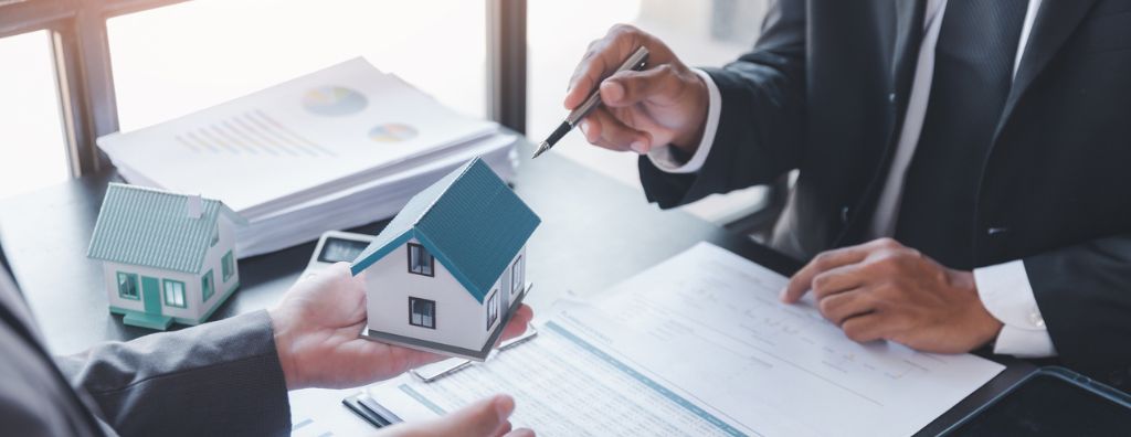 A close up of a real estate agent and client’s hands. The real estate agent explains common buying and selling mistakes in real estate.