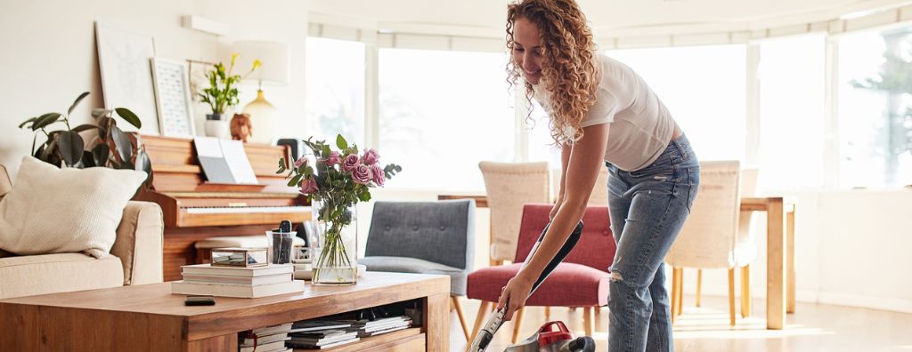 A woman vacuums her living room carpet as she spends the day cleaning her home