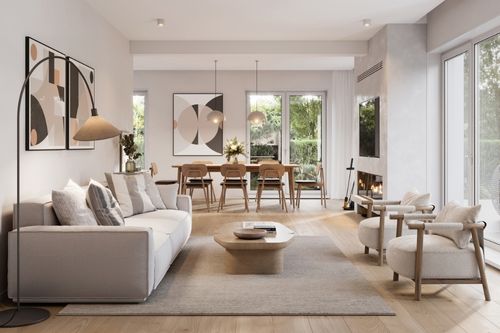 The interior of a modern home open-concept living room/dining room area with minimalist decorations and features: neutral-colored carpet, hardwood floors, beige couch and chairs, and a fireplace in the dining room.