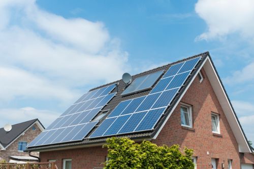 A brick home with solar panels covering its steep roof.