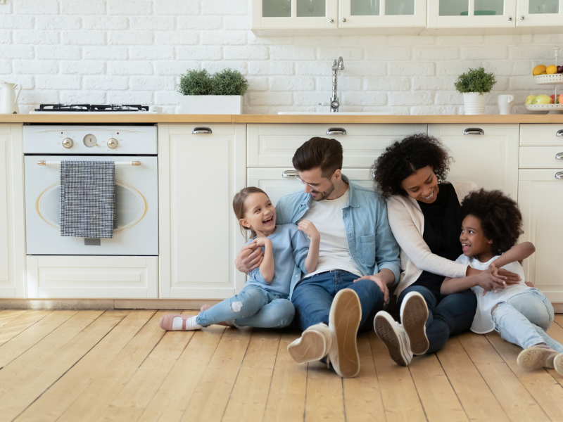 A family sits on their kitchen floor.