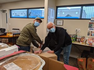 Two men unpack a box of food donations for a Thanksgiving meal.