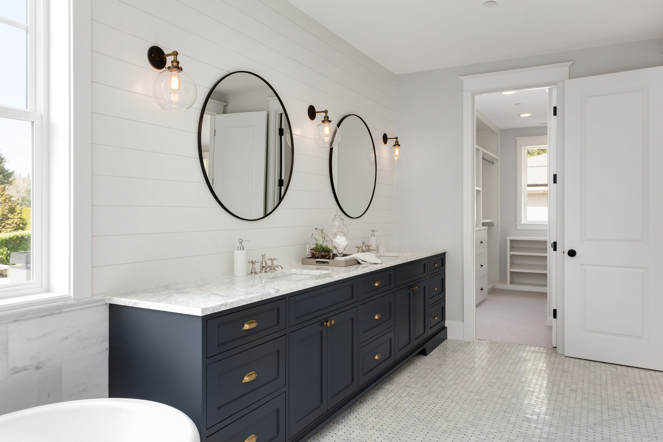 A bathroom with a dark blue vanity, white walls, and white tile.