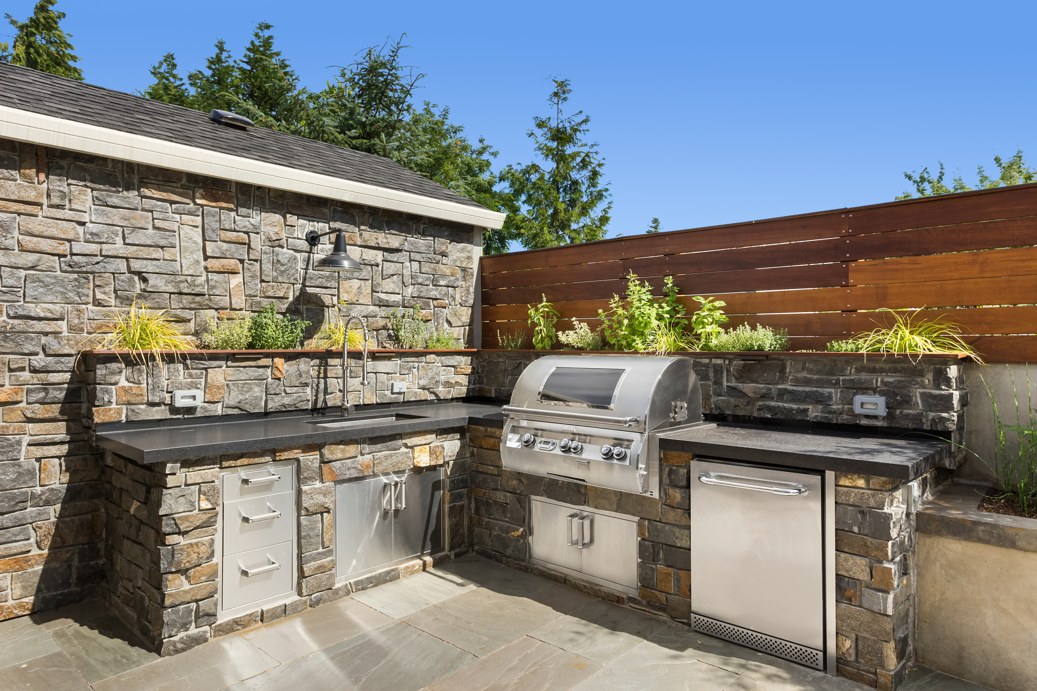 An outdoor kitchen with a sink, barbecue, and dishwasher.