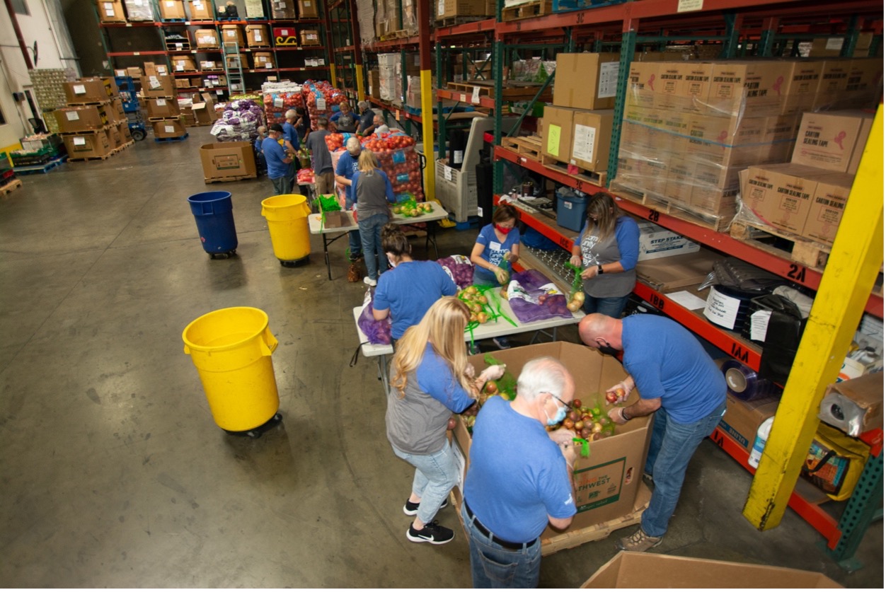 A group of people bag produce in a warehouse.