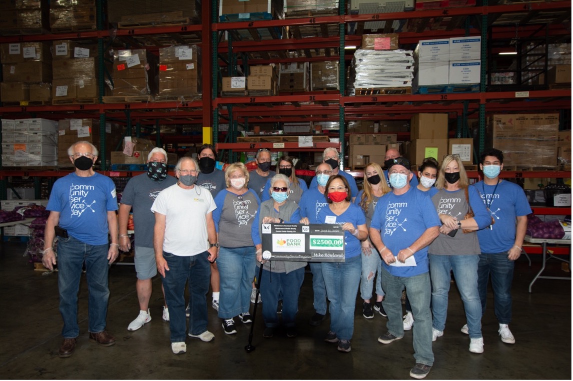 A group of people hold up a check in a warehouse.