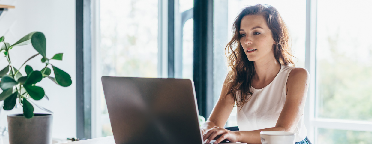 A woman types on her laptop at home.