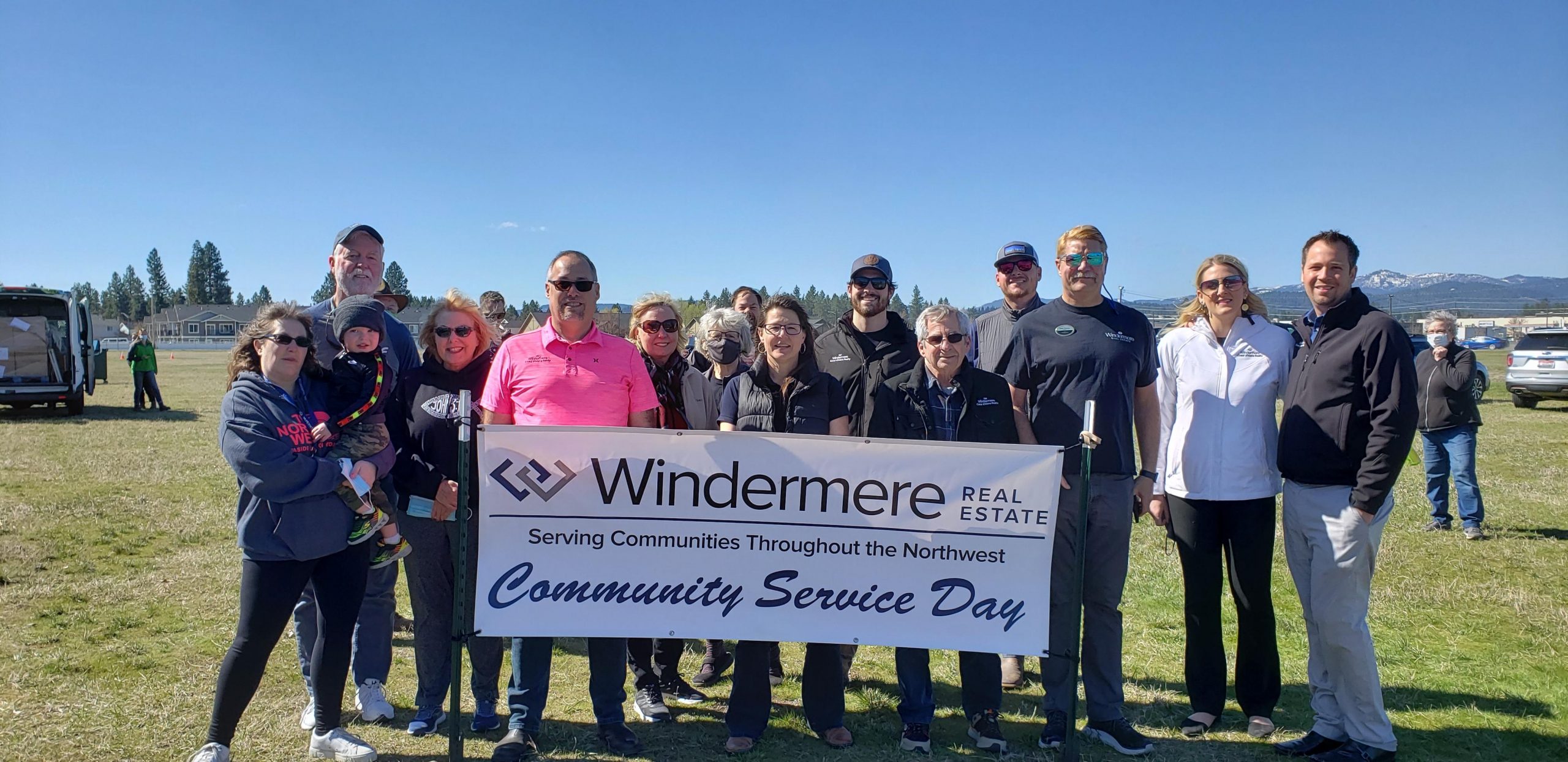 A group of people hold a Windermere Community Service Day banner. 