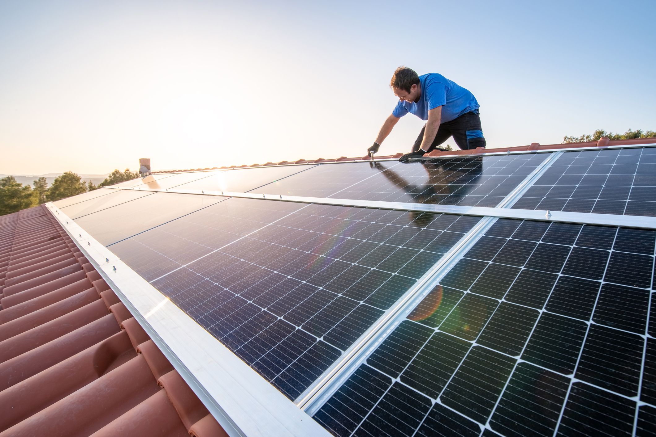 A man installs solar panels on the roof of a house.