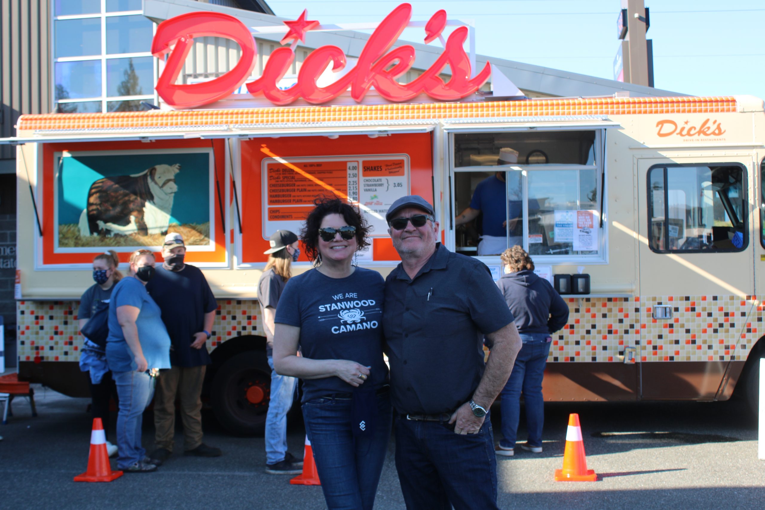 A man and a woman stand together in front of a food truck.