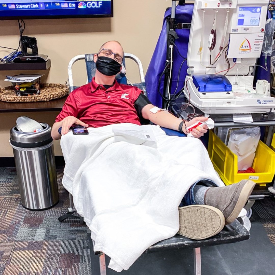 A man sits in a chair getting his blood drawn.