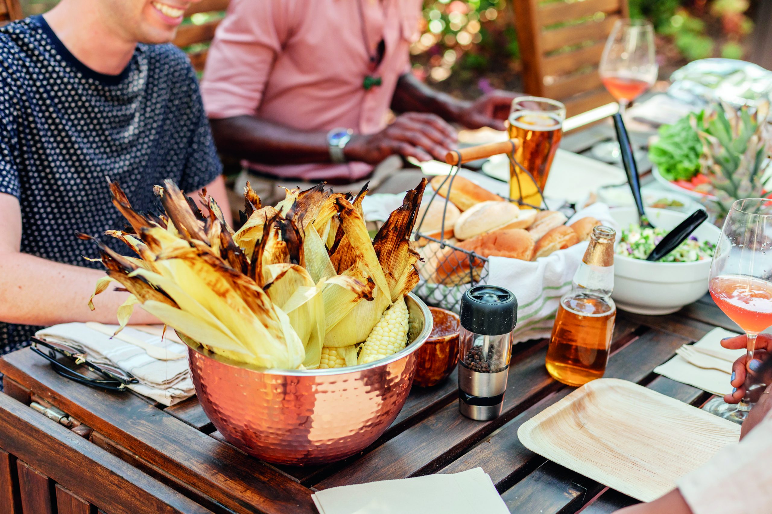 A group of people sit at a table outside for a backyard barbecue.