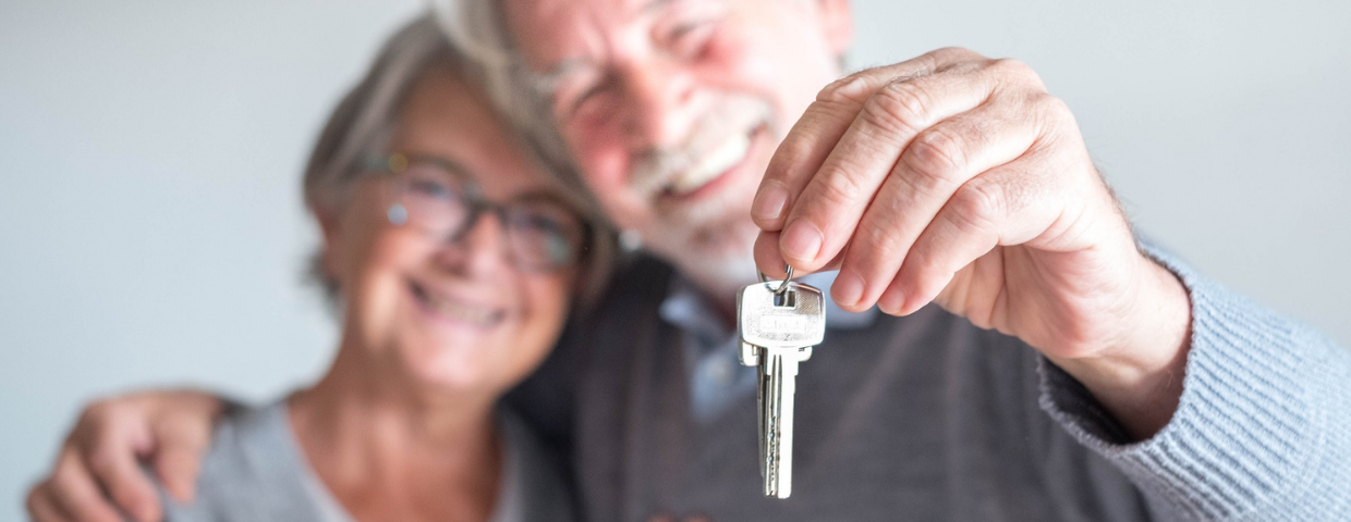 An elderly man and woman hold the keys to their new home.