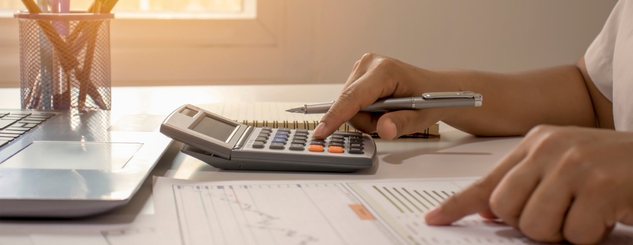 A young man sits at his desk and calculates the cost of buying a home.