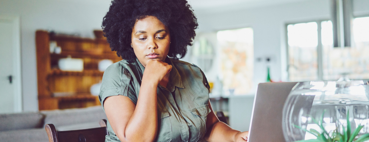 A woman examines financial paperwork at her desk.