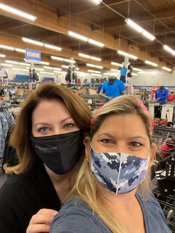 Two women with masks on take a selfie during a clothing drive for local schoolchildren. 