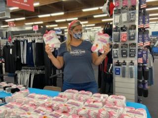 A woman in mask holds up pairs of socks during a clothing fundraiser for local schoolchildren.