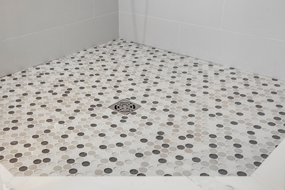 A shower floor of neutral-colored penny tile.