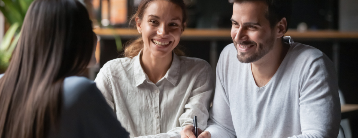 Happy couple ready to sign their closing documents with their real estate agent.