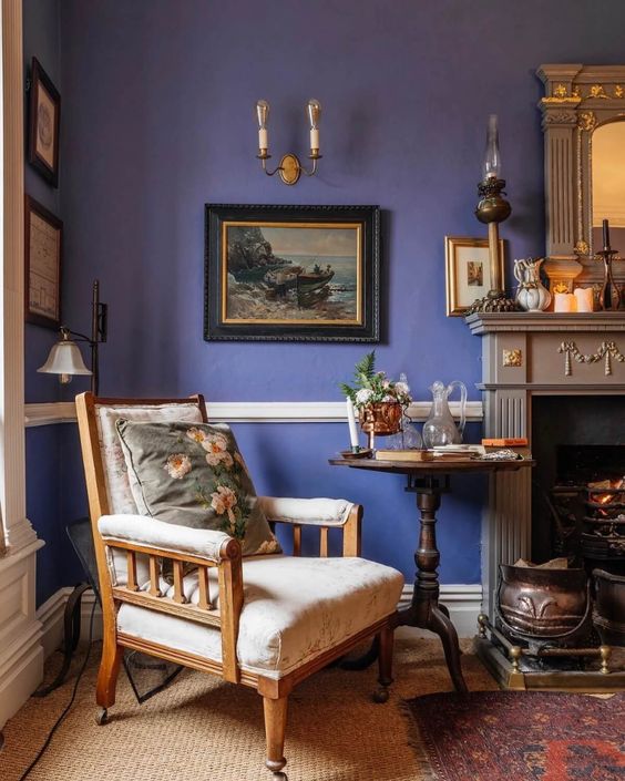 The corner of a living room with a comfortable chair, a periwinkle blue wall, and a fireplace mantel.