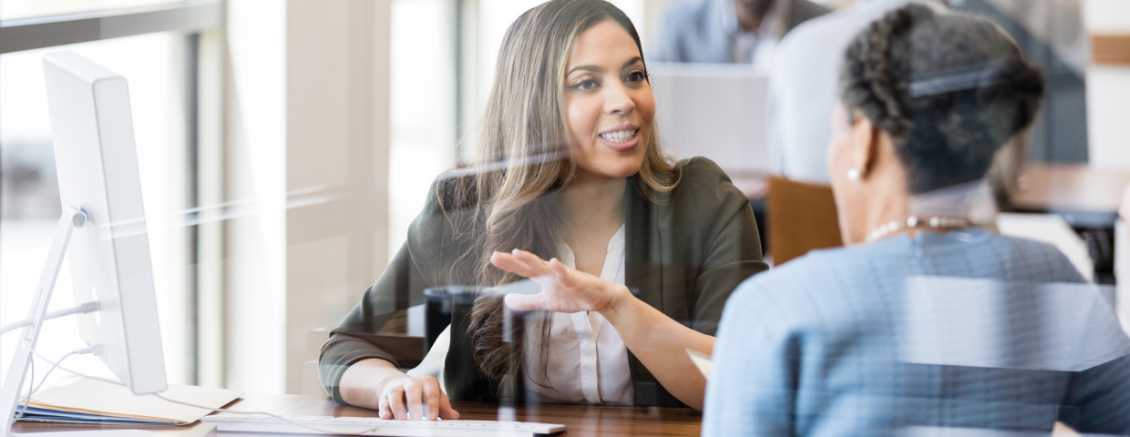 A real estate agent talks to her client at her computer.