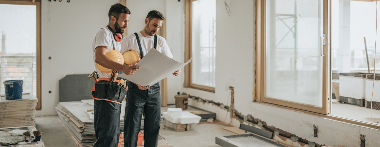 Two young male contractors look at blueprints as they prepare to begin a remodel.