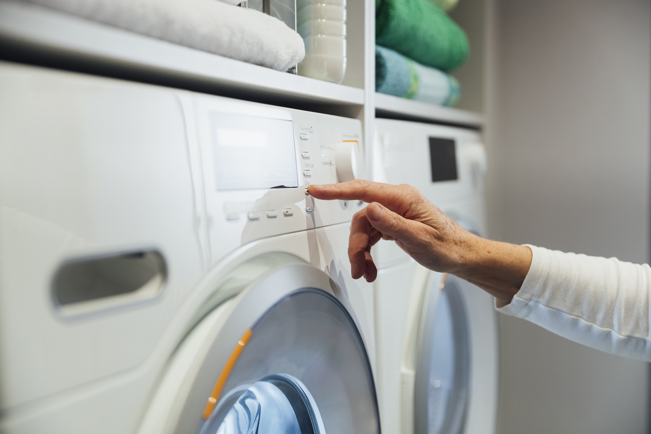 A close-up of a person’s hand starting their dryer. 