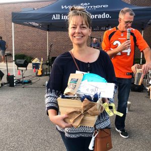 A woman in the foreground holds a basket of donated items and a man in a football jersey behind her carries some items.