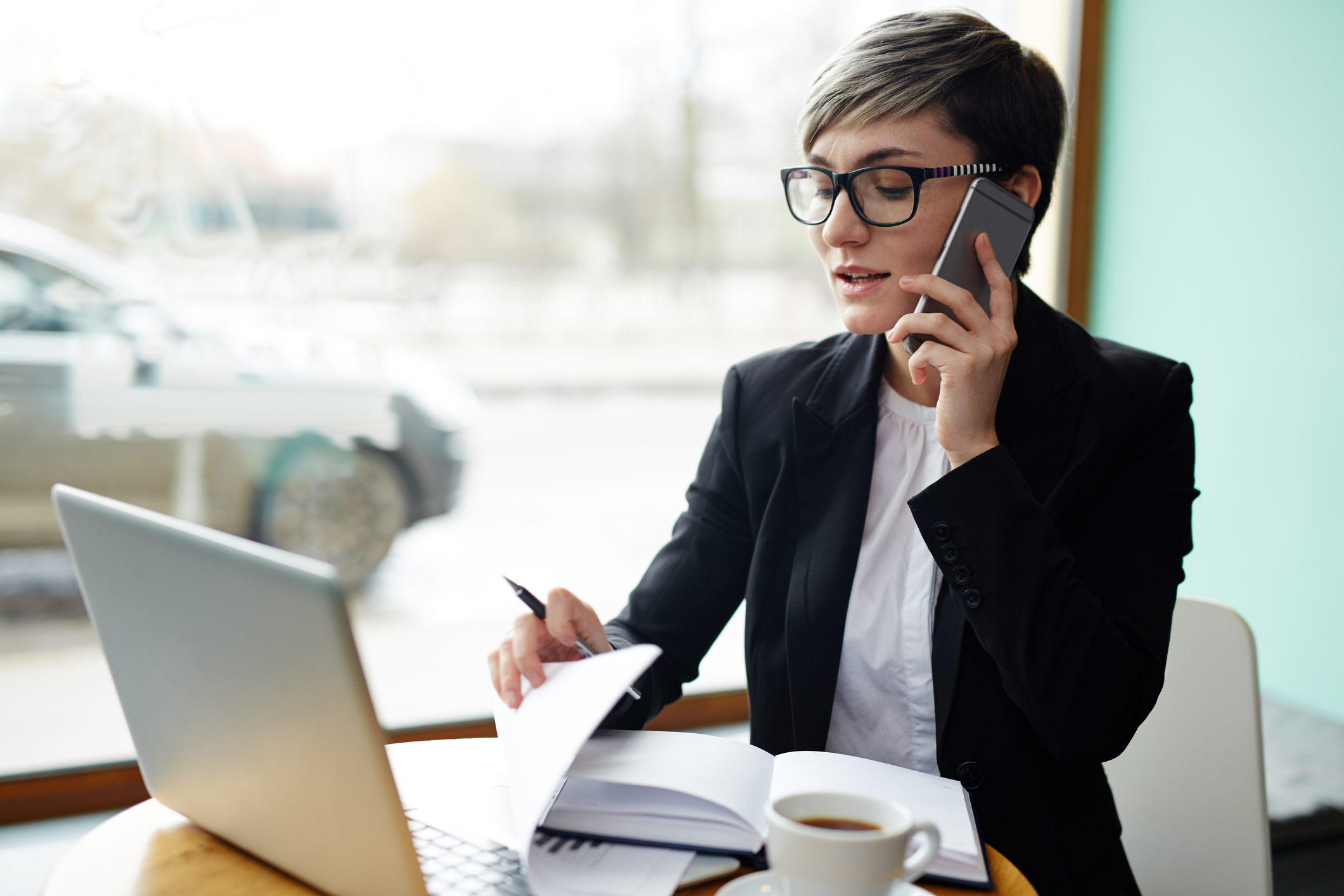 A real estate agent talks to a client on the phone while working on their laptop.