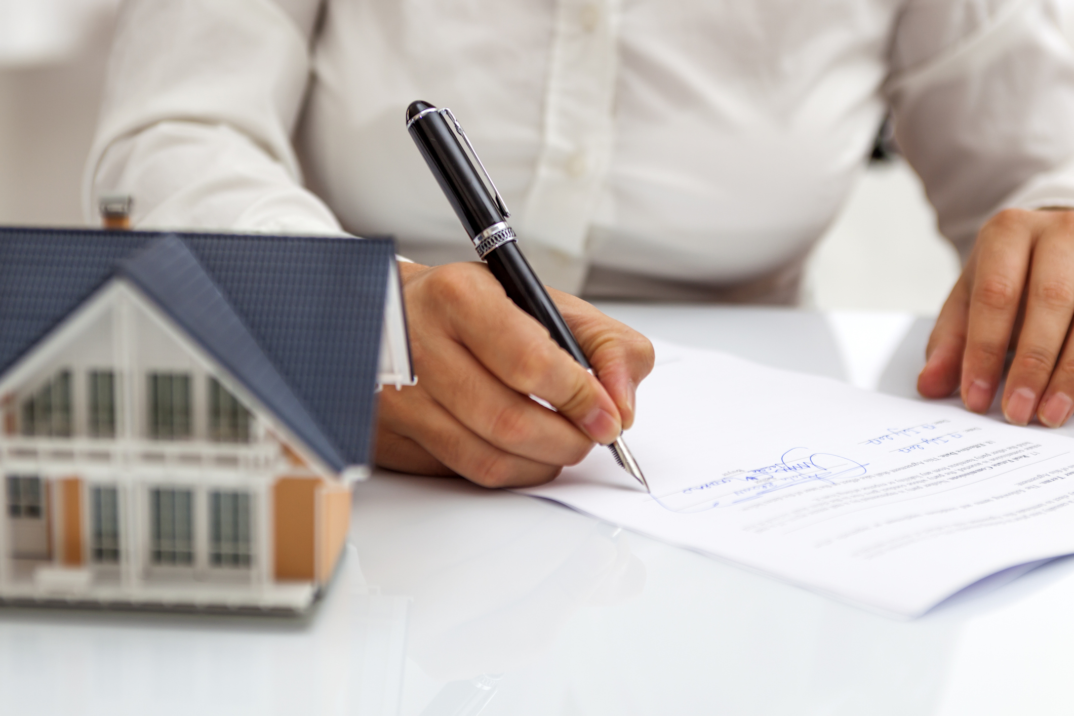 A woman sits at a table signing her mortgage paperwork.