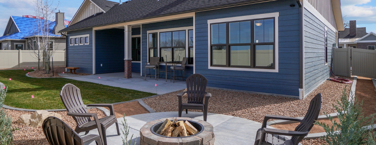 A modern home with a professionally landscaped backyard and paved firepit.