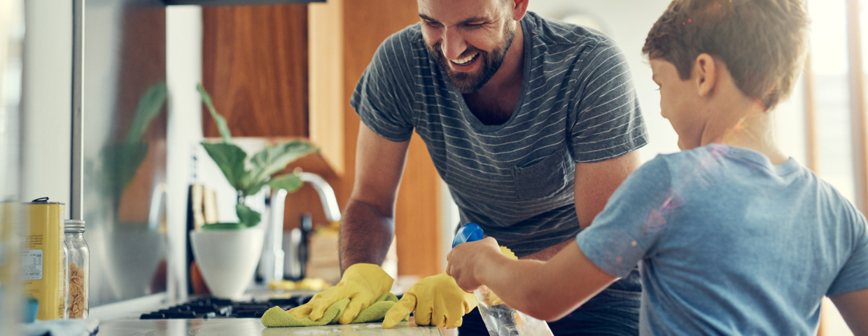 A man and his son scrub off their kitchen counter.