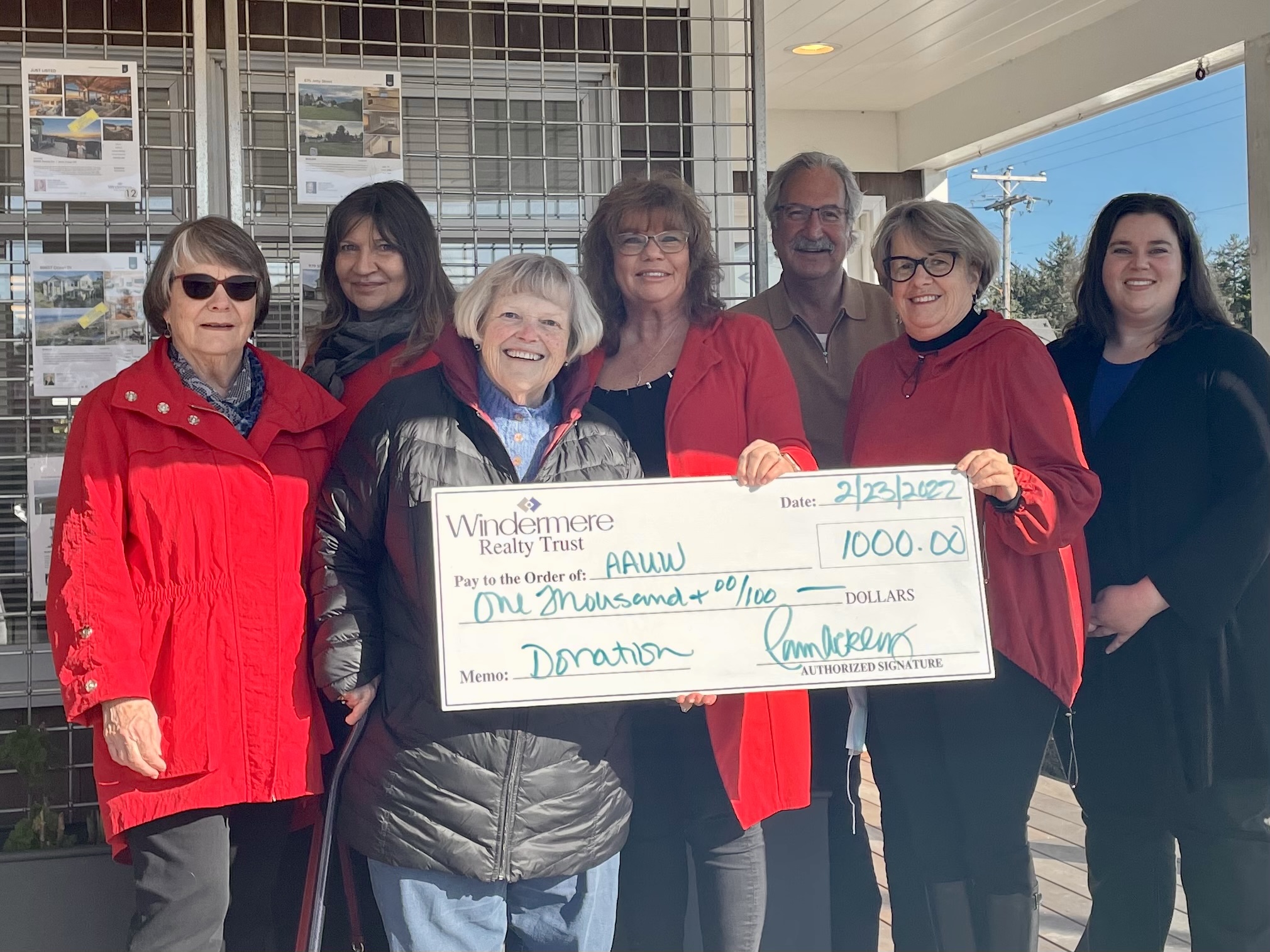 A group of people hold up a check for $1,000.