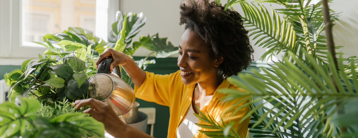 A young woman waters her houseplants.