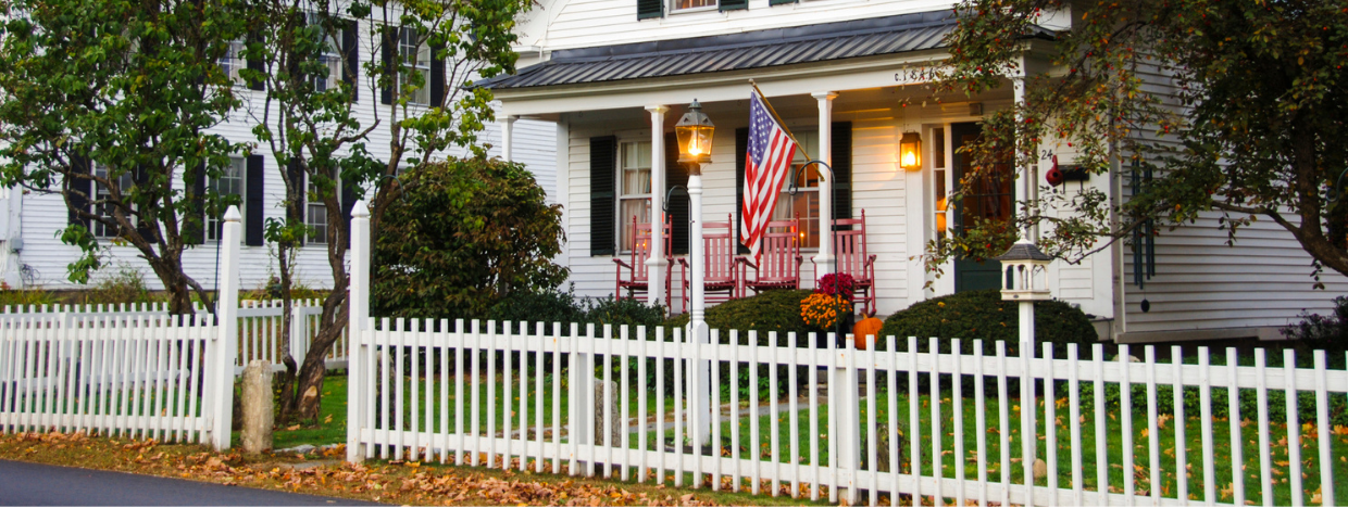 A traditional home with a white picket fence in the front yard.