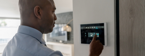 A man sets his house alarm on a smart home tech system.