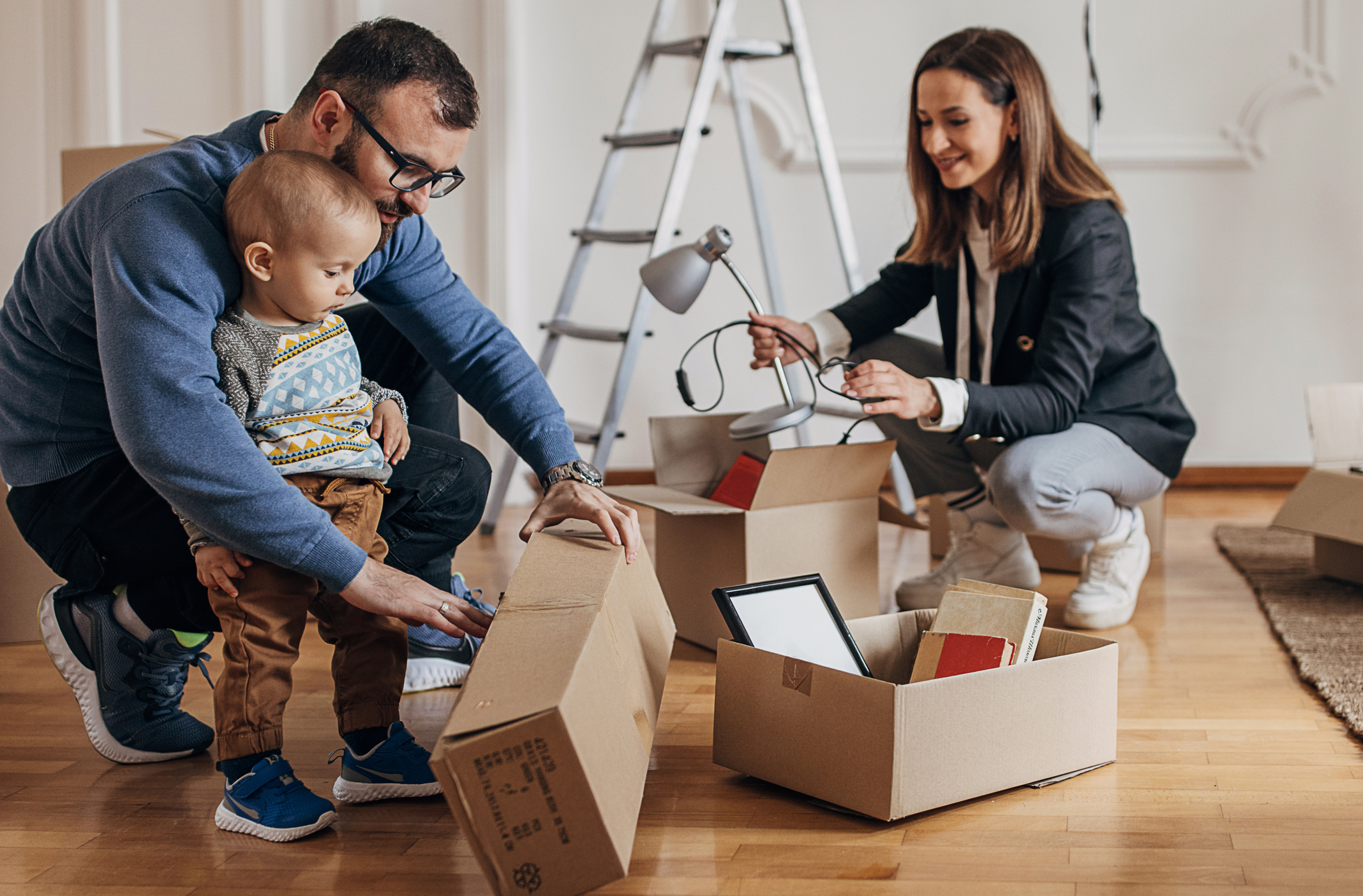 A young couple and their baby unpack boxes in their new home.