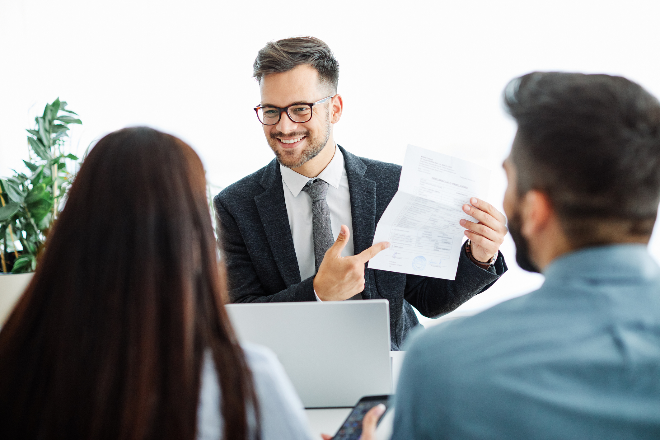 A real estate agent and his clients examine a real estate contract.