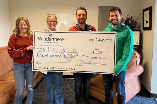 Three agents from Windermere Bozeman and a rep from Haven hold up a donation check for one thousand dollars