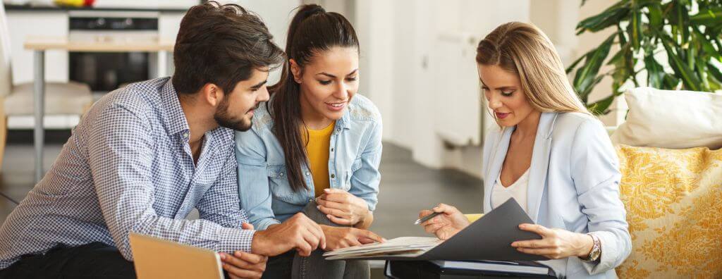 Man and a woman looking at real estate paperwork with their real estate agent