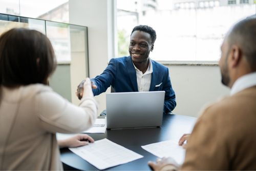 A mortgage broker shakes hands with a man and a woman as they secure the terms of their adjustable-rate mortgage