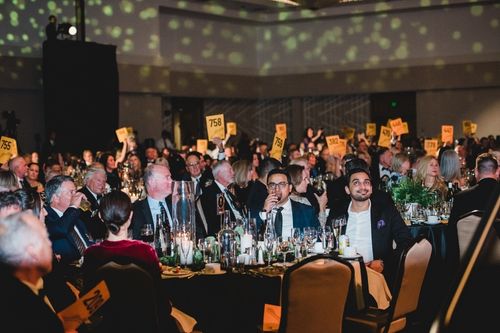 Windermere Foundation Gala attendees hold their bidder numbers in the air as they contribute to Raise the Paddle, collectively raising $520,250 in donations.