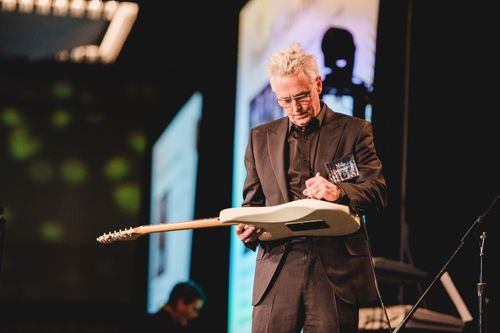 Pearl Jam guitarist Mike McCready signs an electric guitar on stage at the Windermere Foundation gala. The item would go up for auction as part of a Pearl Jam package.