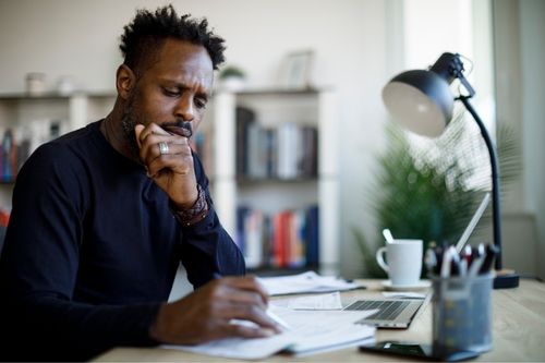 Adult man calculating finances in his home office as he prepares to buy a house