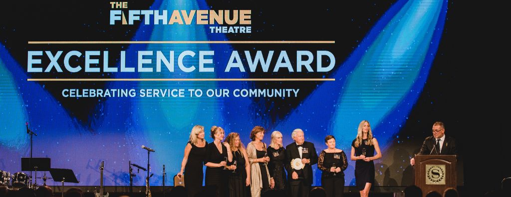 On stage at the Windermere Foundation Gala at the Sheraton Grand, members of Windermere Real Estate senior leadership receive the Excellence Award from the 5th Avenue Theatre on behalf of the Windermere Foundation