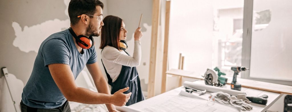 A man and a woman in the midst of remodeling their home discuss whether they should continue with a renovation project