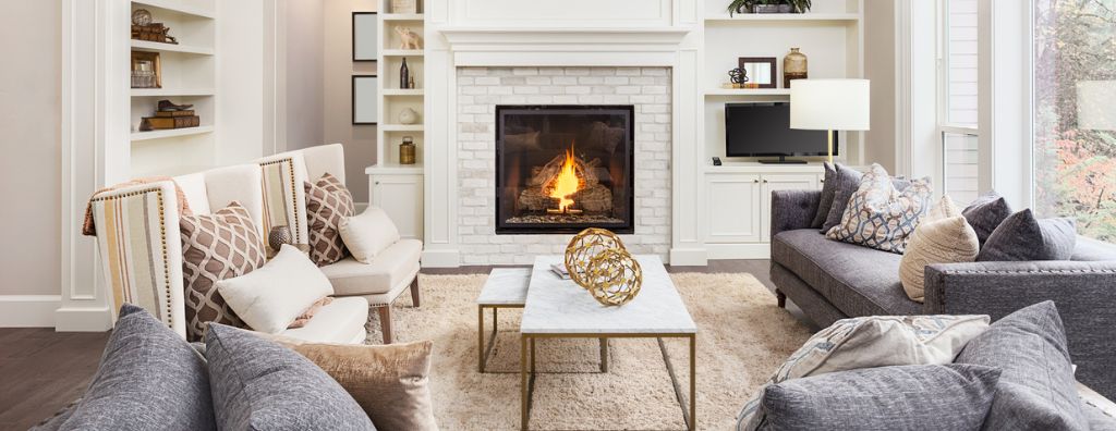 A living room in a modern home decorated with some of the top interior design trends for 2023 including earth tones like off-white, light browns, and blues and organic materials like linen and marble.